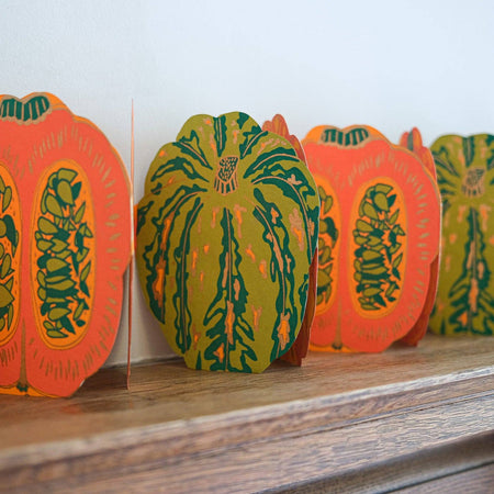 Decorative paper pumpkins with intricate designs on a wooden surface. Pumpkin Handprinted Garland | East End Press | Shop Fodder