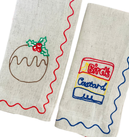 Two embroidered fabric items with a Christmas pudding and Birds Custard design on a white background. See & Quin | Embroidered Linen Napkins | Shop Fodder