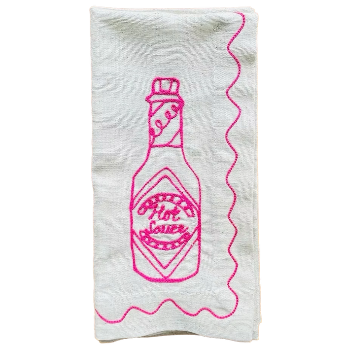 White towel with pink embroidered hot sauce bottle design on a white background. Embroidered Linen Napkins | See & Quin | Shop Fodder