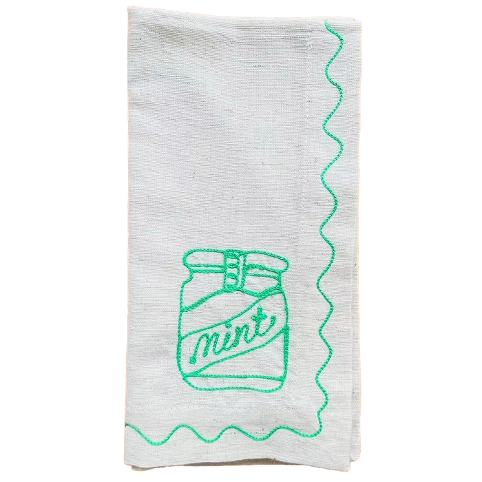 White towel with green embroidered design of a jar labeled 'mint' on a white background. Embroidered Linen Napkins | See & Quin | Shop Fodder