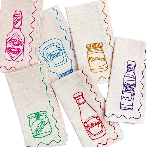 Set of fabric napkins with colorful condiment illustrations on a white background. Embroidered Linen Napkins | See & Quin | Shop Fodder