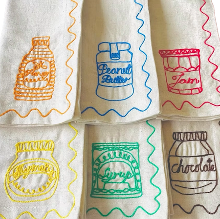 Set of embroidered napkins with colorful illustrations of food items on a white background. Embroidered Linen Napkins | See & Quin | Shop Fodder