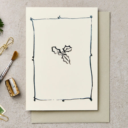 Greeting card with minimalist design on a textured surface with stationery items.