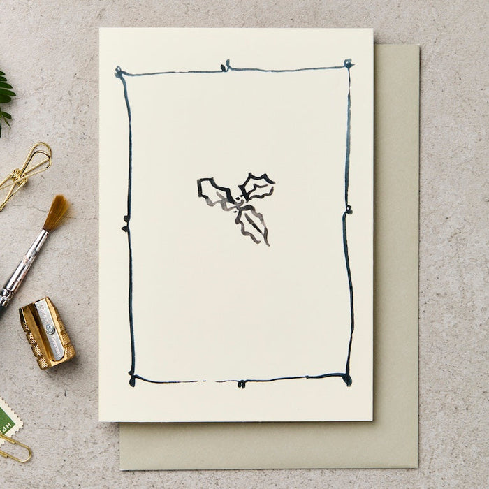 Greeting card with minimalist design on a textured surface with stationery items.