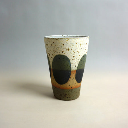 Speckled ceramic cup with green and orange design on a gradient background. Sophie Alda | Shop Fodder