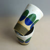 Ceramic cups with green and blue abstract designs on a neutral background. Sophie Alda | Shop Fodder