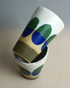 Ceramic cups with green and blue abstract designs on a neutral background. Sophie Alda | Shop Fodder