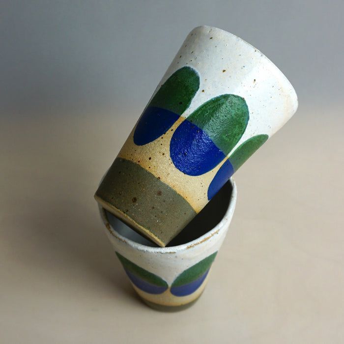 Ceramic cups with green and blue abstract designs on a neutral background. Sophie Alda | Shop Fodder