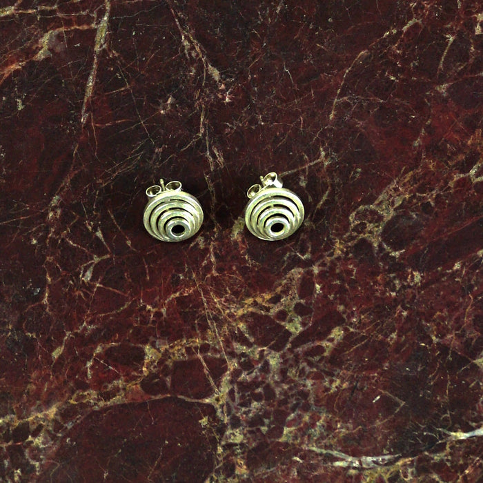 Pair of gold spiral earrings on a marbled surface  | Mini Nudge Studs in Sterling Silver | Scarlett French | Shop Fodder