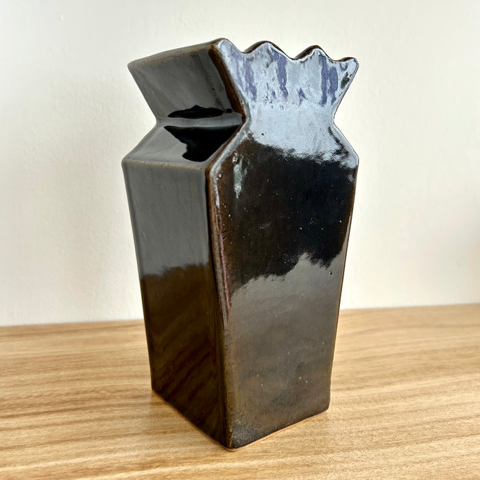 Black ceramic vase with wavy top on a wooden surface. Studio ERS | Ceramic Vase | Shop Fodder