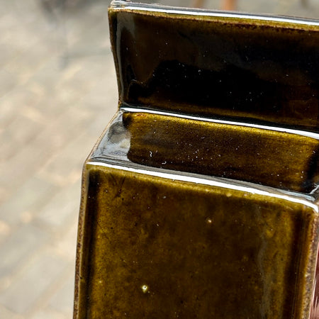 Close-up of a brown ceramic tile with a blurred background. Studio ERS | Ceramic Vase | Shop Fodder