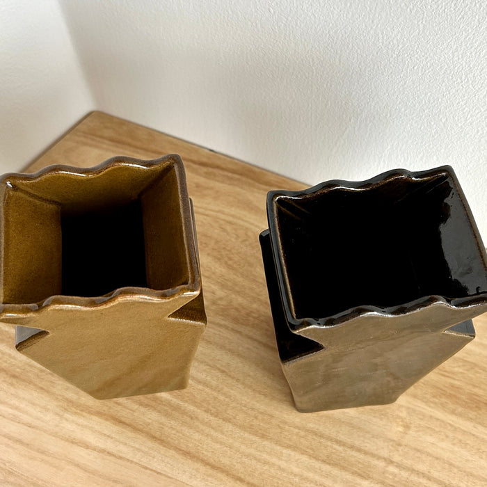 Two decorative vases, one gold and one black, on a wooden surface. Studio ERS | Ceramic Vase | Shop Fodder