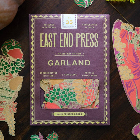 Pack of East End Press Garland printed paper on a wooden surface with decorative cutouts.Thanksgiving Handprinted Garland | East End Press | Shop Fodder