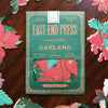 East End Press Garland paper package on a wooden surface with floral cutouts. East End Press | Shop Fodder