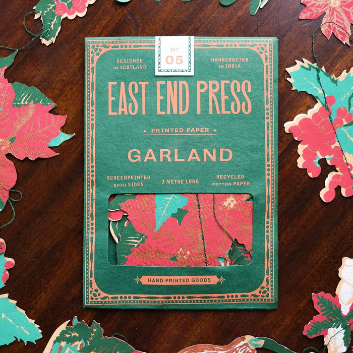 East End Press Garland paper package on a wooden surface with floral cutouts. East End Press | Shop Fodder