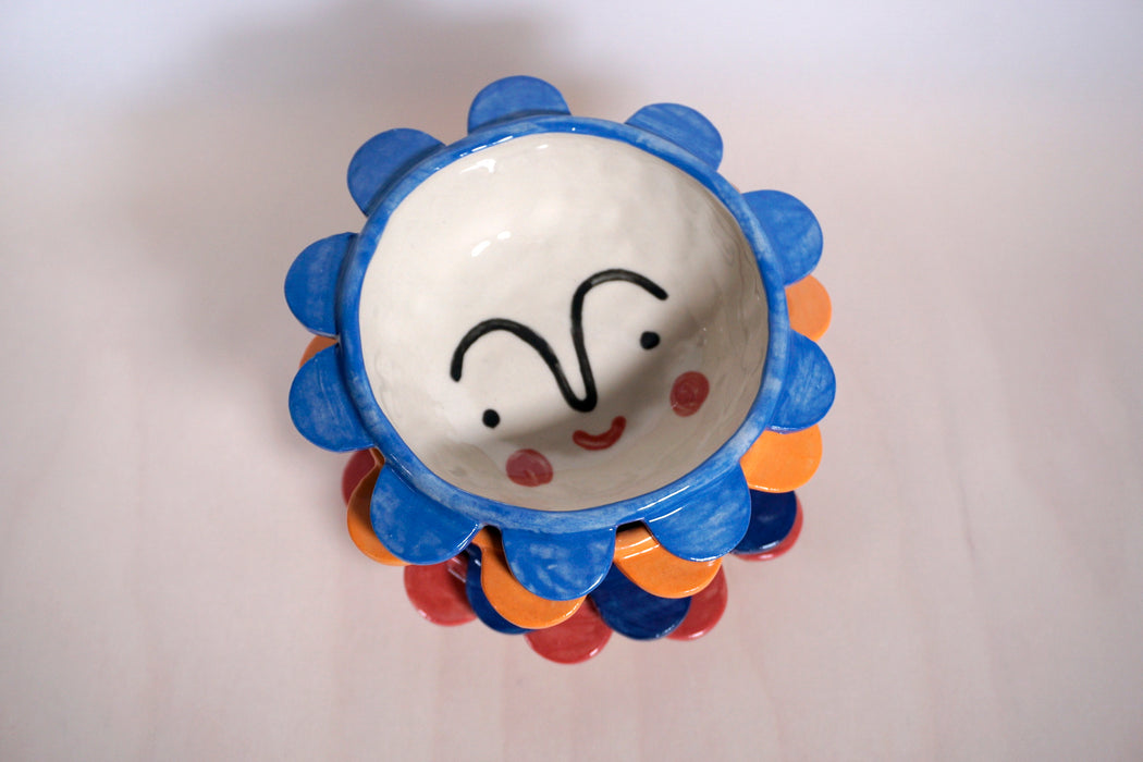multicoloured dishes with flower pattern and a face on the bottom. all in a stack. 