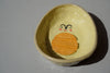ceramic soap dish made to look like an avocado cut in half with a face drawn on to it. 