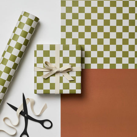 Green and white checkered gift box with ribbon, scissors, and wrapping paper on a white and brown background. | Kinshipped | Shop Fodder
