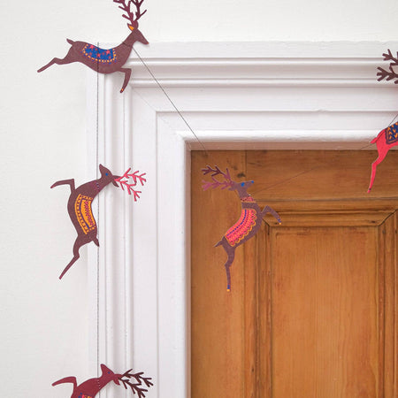 Decorative paper reindeer hanging on a white wall and wooden door. | East End Press | Shop Fodder