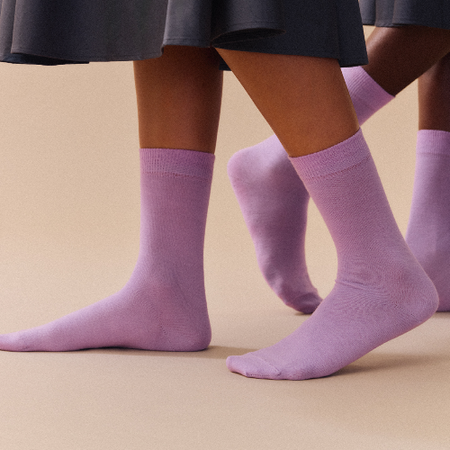 Purple socks worn with a dark skirt on a beige background. Pairs Socks | Shop Fodder