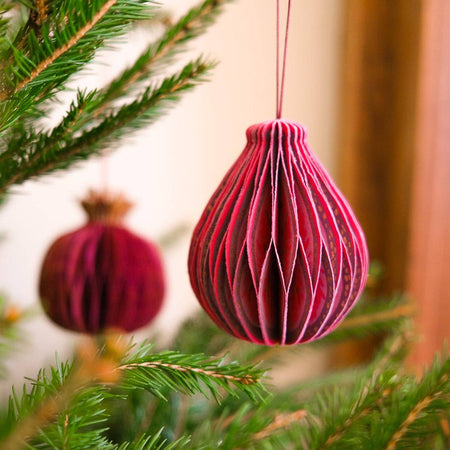 Pink decorative ornament hanging on a Christmas tree branch | East End Press | Shop Fodder