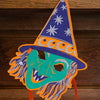 Colorful witch hat with a face design on a wooden background. Masks | East End Press | Shop Fodder