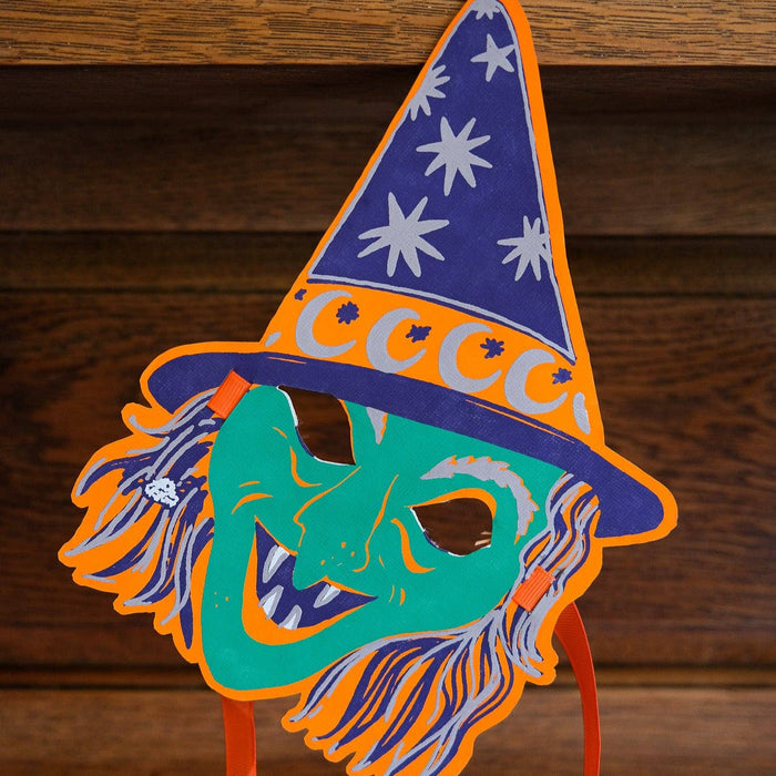 Colorful witch hat with a face design on a wooden background. Masks | East End Press | Shop Fodder